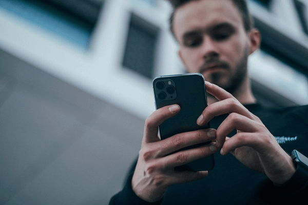 Illustration: A man reviewing sports betting odds on a smartphone.
